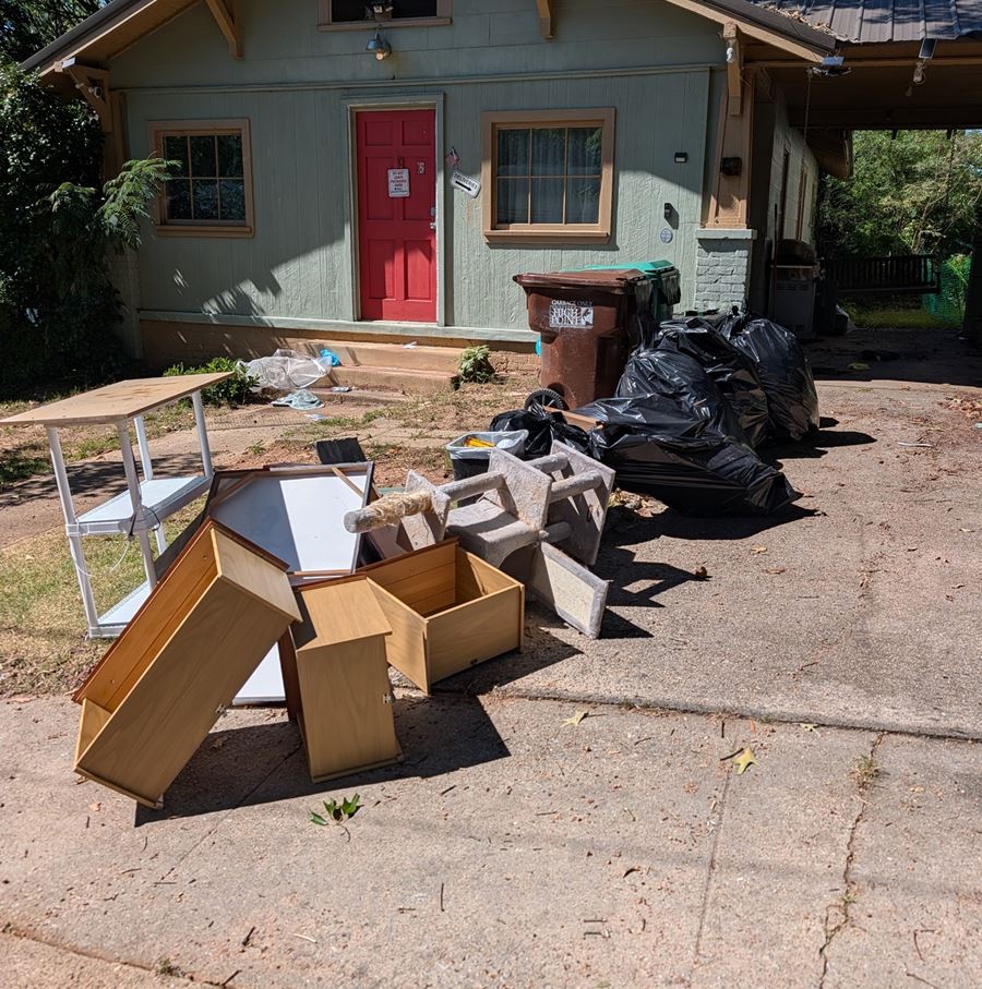 Before: furniture, shelving, and bagged trash piled in a driveway in front of a small house in Davie County NC