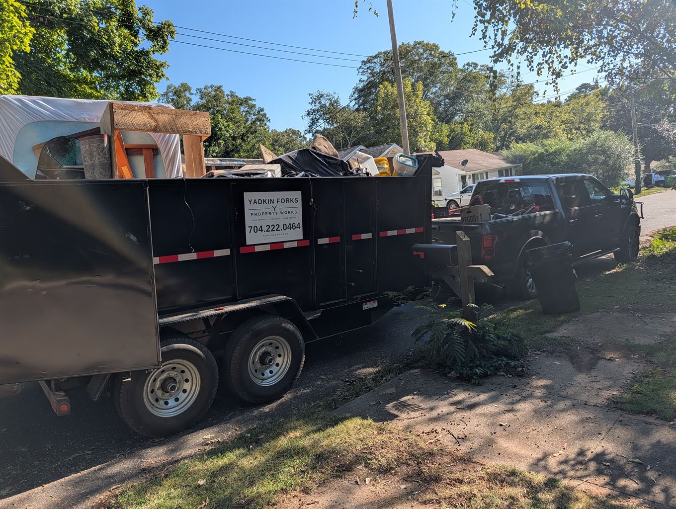 Yadkin Forks 14 foot high-side dump trailer loaded with furniture and household junk, hitched to a truck in a driveway in Davie County NC